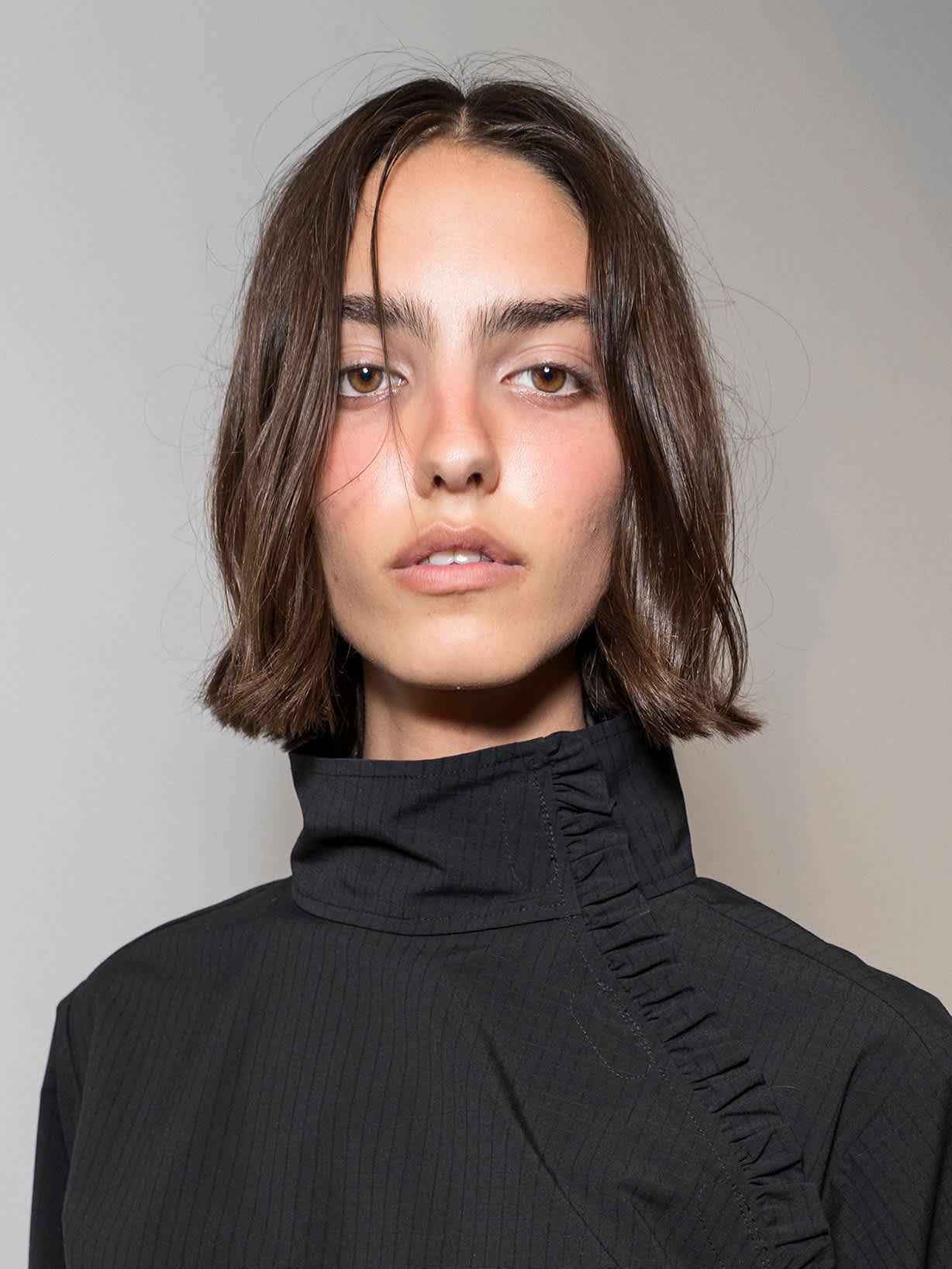 Frau mit brünettem Bob trägt den Make-up-Trend Blurred Lips
