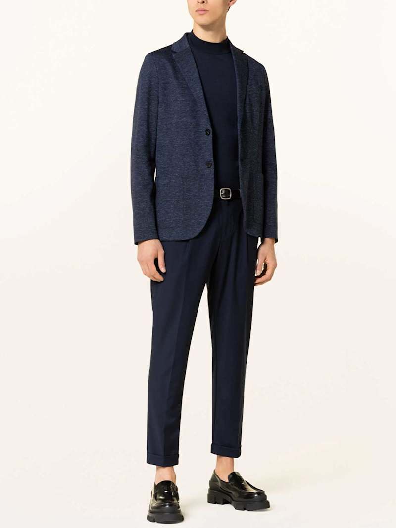 Mann in einem dunkelblauen Sakko mit passender Hose und Loafers