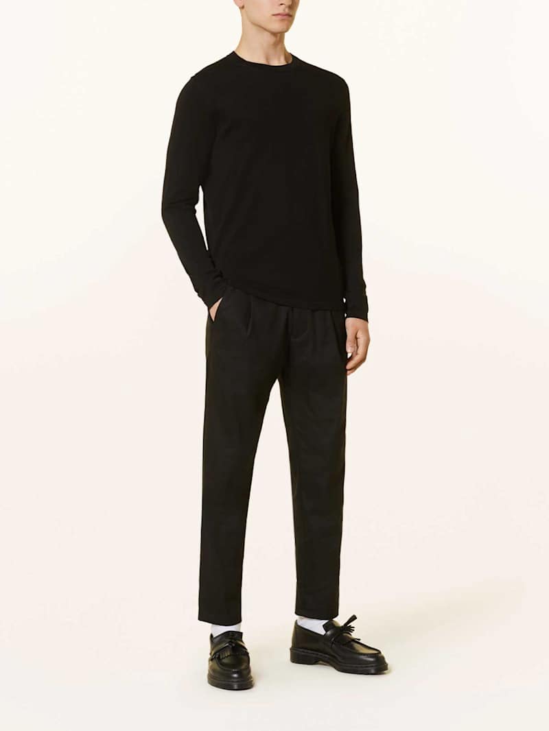 Mann trägt einen schwarzen Pullover zu einem Smart Casual Outfit