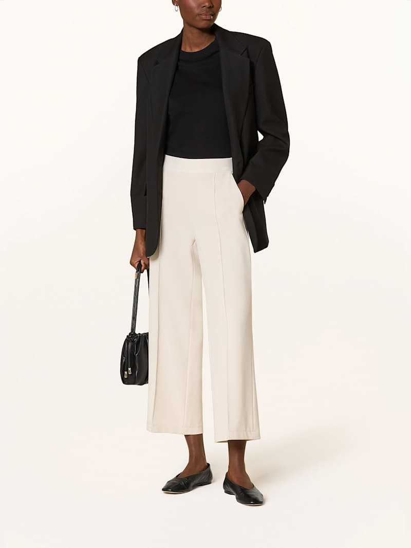Frau trägt eine beige Culotte zum schwarzen Blazer und schwarzen Top