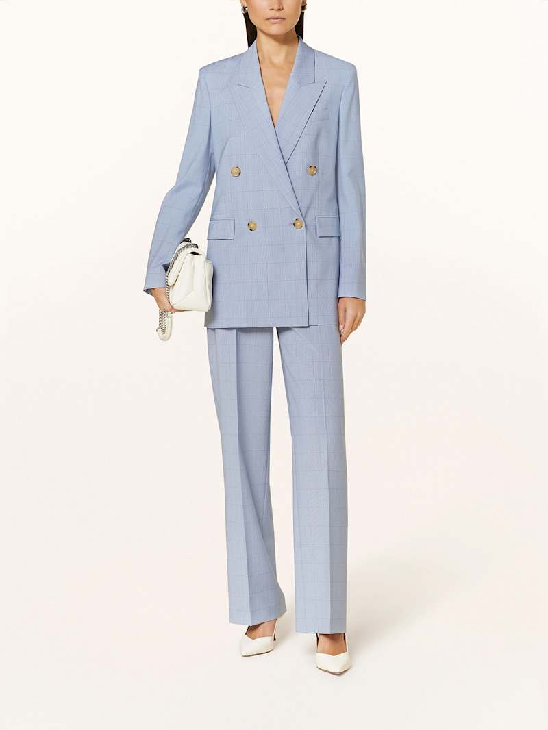 Frau trägt hellblauen Doppelreiher-Blazer zu einer hellblauen Stoffhose