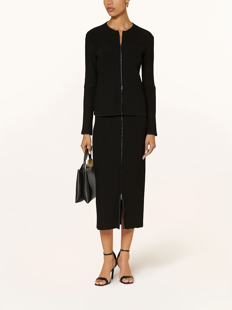 Frau trägt einen schwarzen Bleistiftrock aus Strick mit Reißverschluss