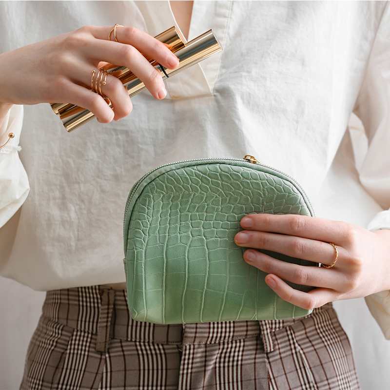 Frau sortiert Make-up in ihre mintfarbene Kosmetiktasche