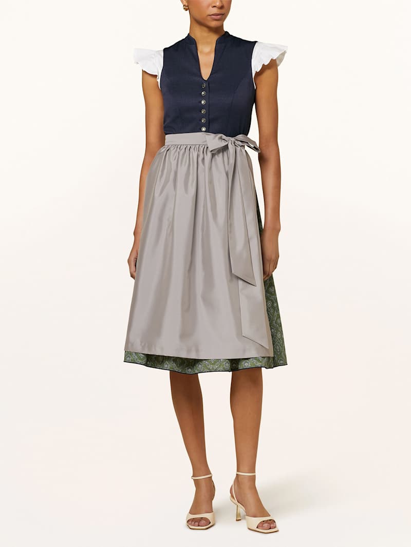 Frau trägt dunkelblaues Dirndl mit Stehkragen und beiger Schürze