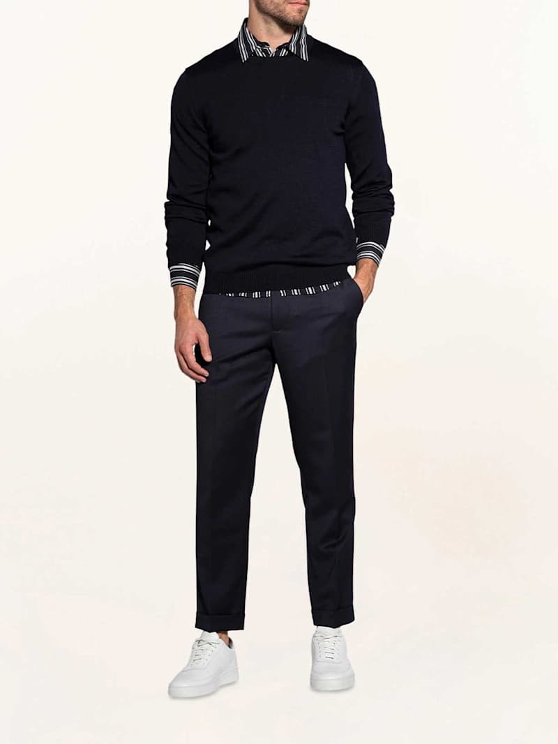 Mann trägt inen schwarzen Pullover über einem Hemd zu einem Business Casual Look