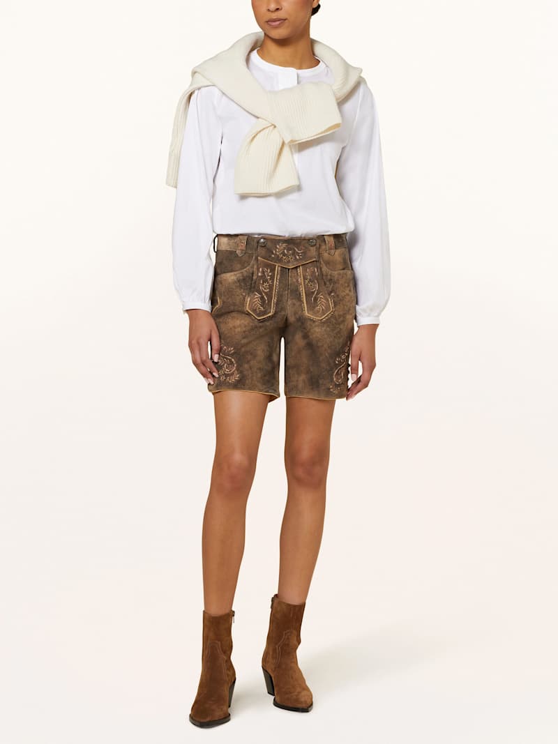 Frau trägt braune Trachtenlederhose mit weißer Bluse