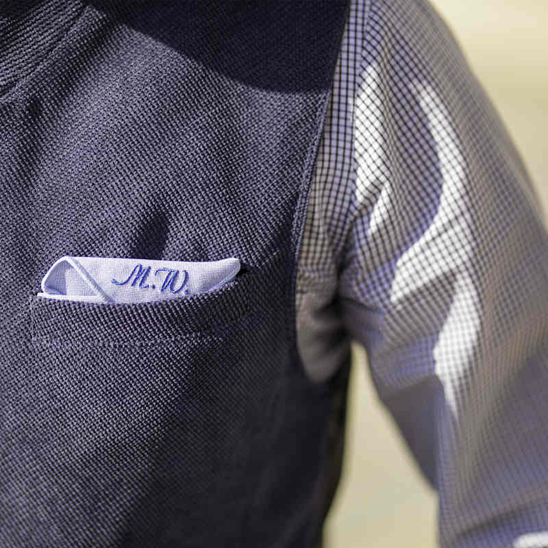 Mann trägt kariertes Trachtenhemd mit blauer Weste und Einstecktuch