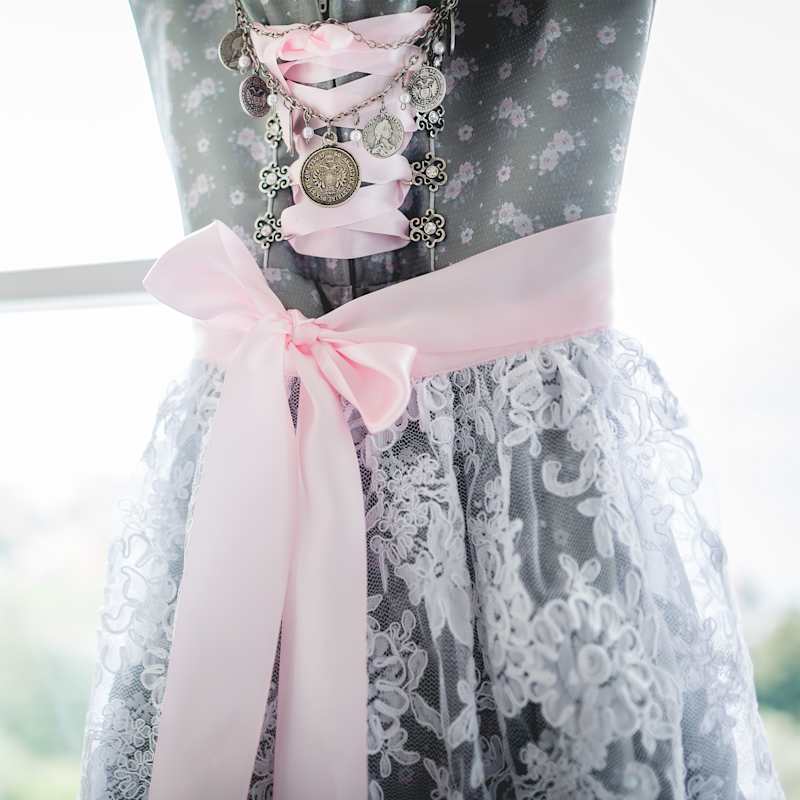 Graues Dirndl mit rosafarbener Schleife und weißer Spitze
