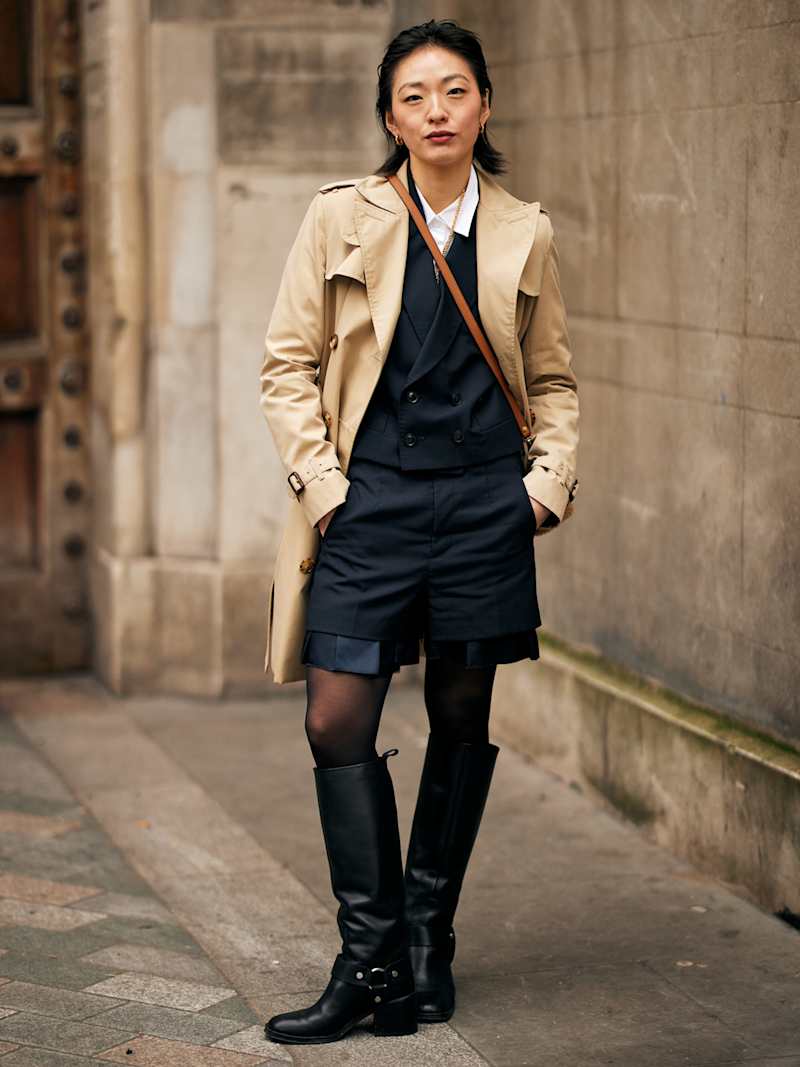 Frau trägt Trenchcoat und Stiefel