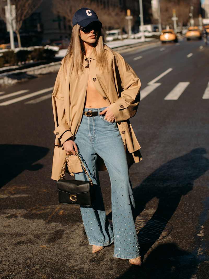 Frau trägt Trenchcoat, Jeans und Cap