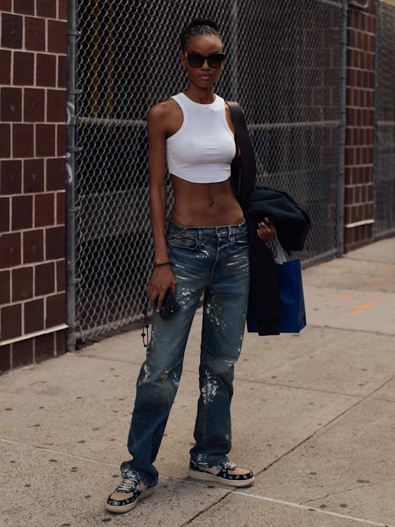 Frau trägt Trenchcoat, Jeans und Cap