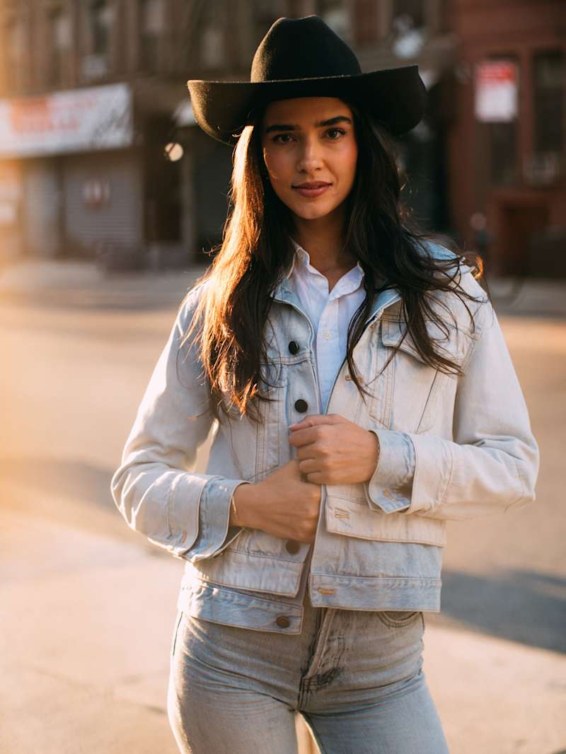 Frau trägt Denim-Outfit und einen Cowboy-Hut