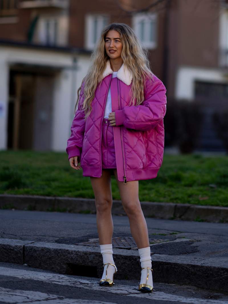Frau trägt eine pinke Steppjacke zum Rock