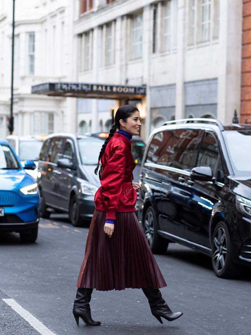 Frau trägt einen roten Plisseerock zu einer Bomberjacke