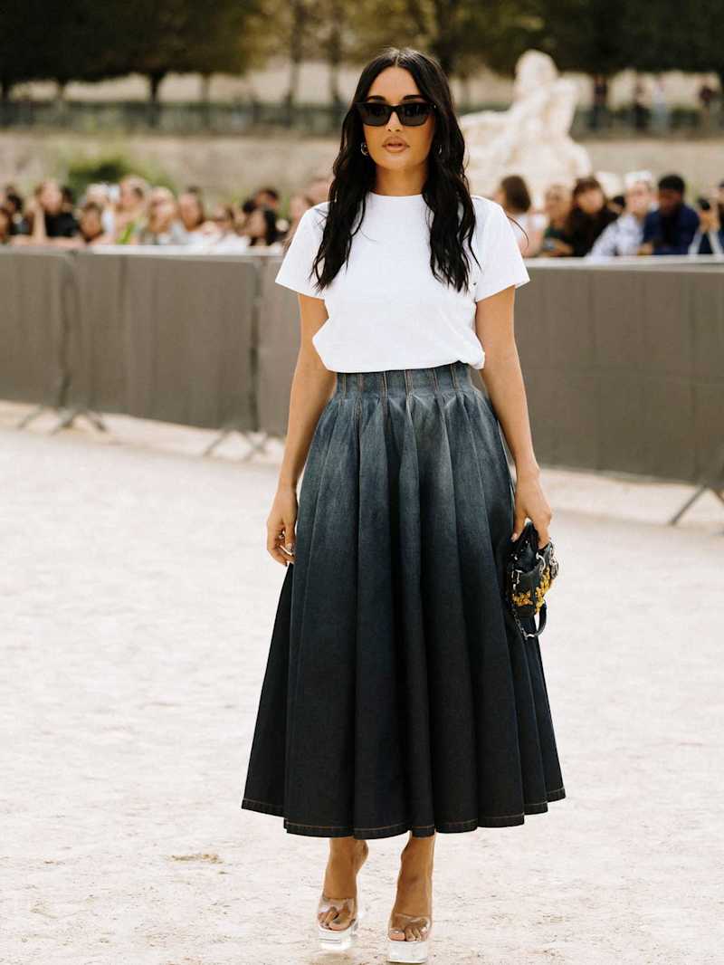 Frau trägt einen langen Denim-Plisseerock zu einem schlichten T-Shirt