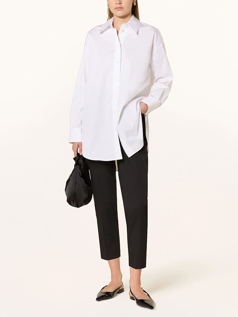 Frau trägt als Smart Casual Look eine schwarze Stoffhose zur weißen Bluse