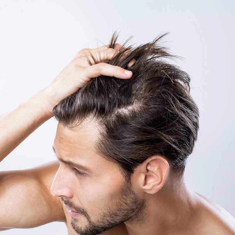 Brünetter Mann fährt sich mit der Hand durch die Haare