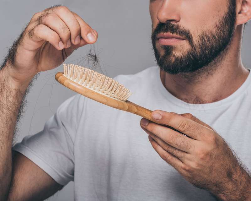 Dunkelhaariger Mann befreit seine Haarbürste von Haaren