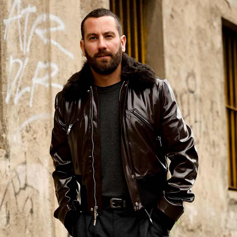 Brünetter Mann mit Buzz Cut und leichten Geheimratsecken trägt schwarze Lederjacke