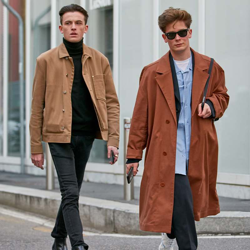 Zwei Männer, einer trägt eine beige Jacke, der andere einen braunen Mantel