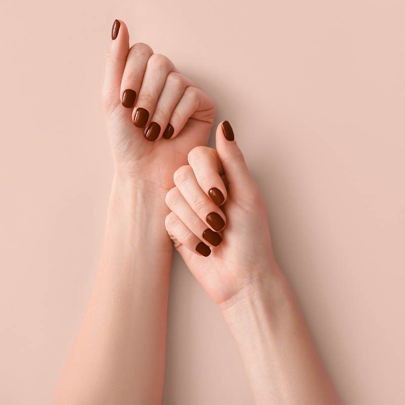 Zwei Hände mit gepflegten Nägeln und dunkelrotem Nagellack