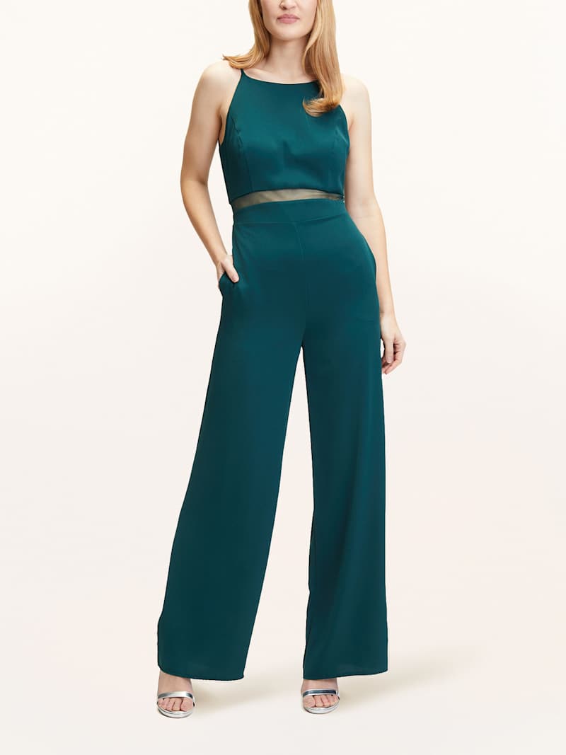 Blonde Frau trägt dunkelgrünen Jumpsuit mit Mesh-Einsatz