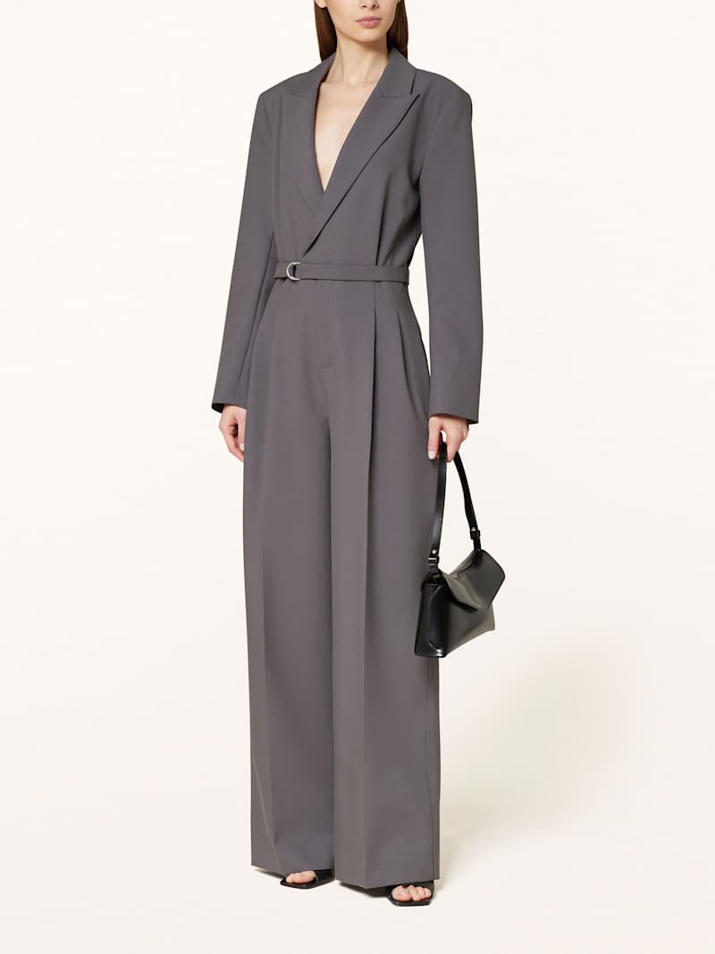 Frau trägt langärmligen Jumpsuit im Blazer-Stil in dunklem Greige
