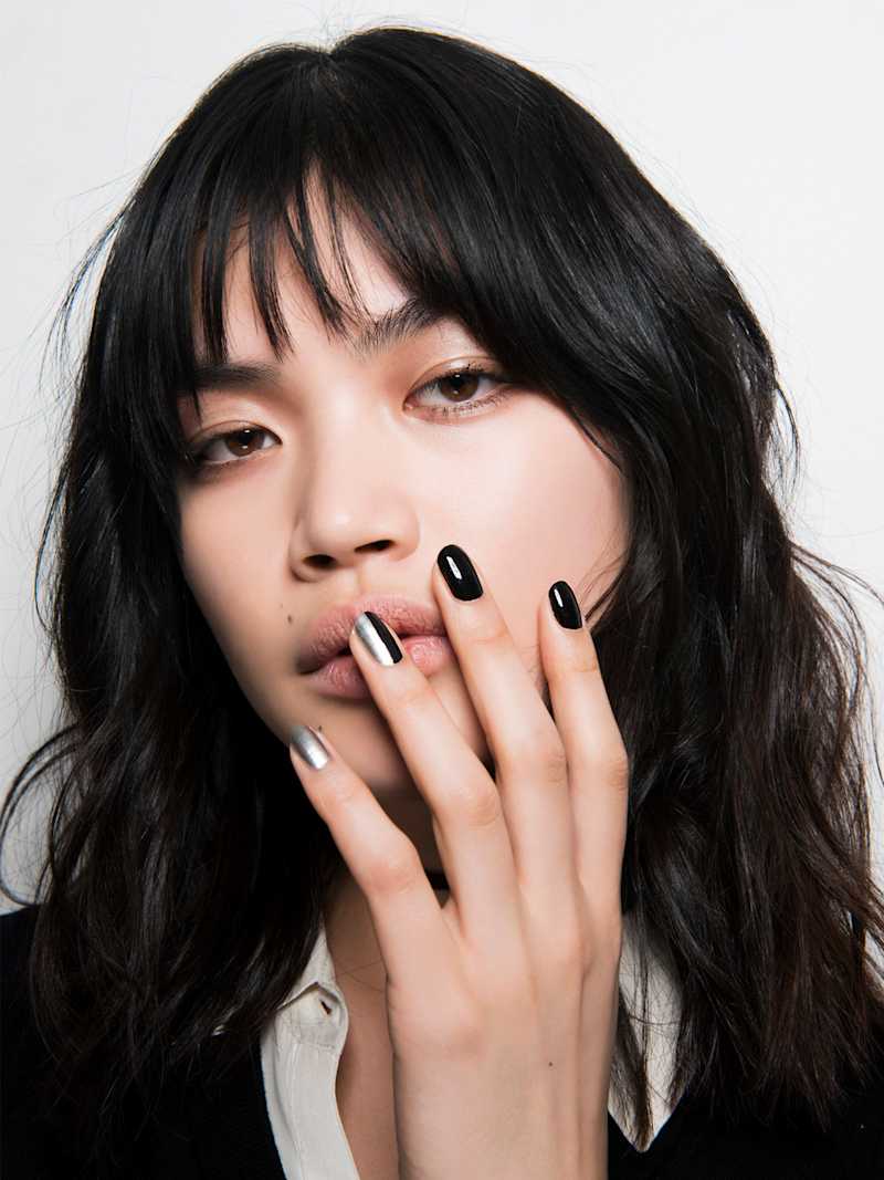 Dunkelhaarige Frau trägt schwarze Nägel und Metallic Nails