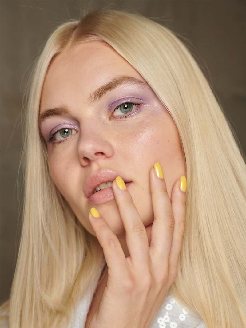 Blonde Frau trägt gelbe Maniküre