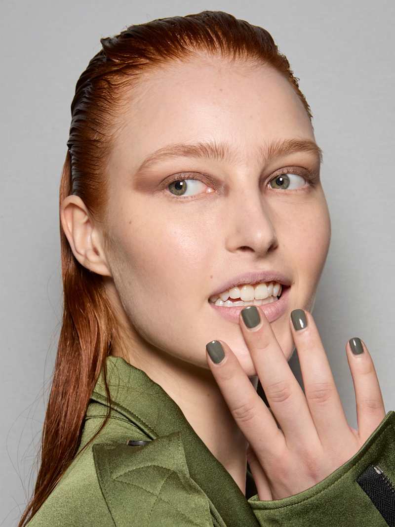 Rothaarige Frau trägt olivgrünen Nagellack