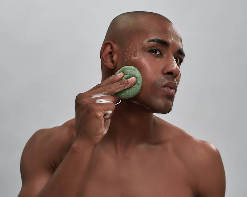 Mann reinigt sein Gesicht mit Schwamm