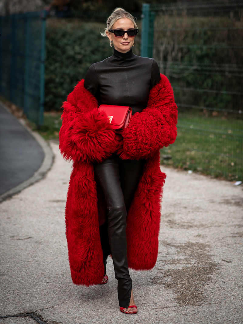 Frau trägt einen schwarzen Leder-Look mit einem roten Mantel
