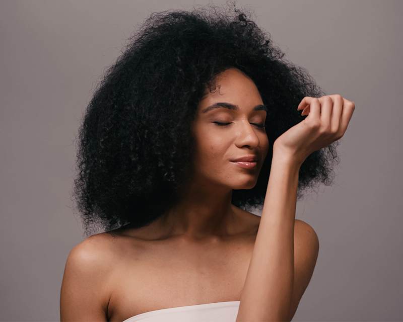 Frau mit dunklen Haaren riecht an ihrem Handgelenk