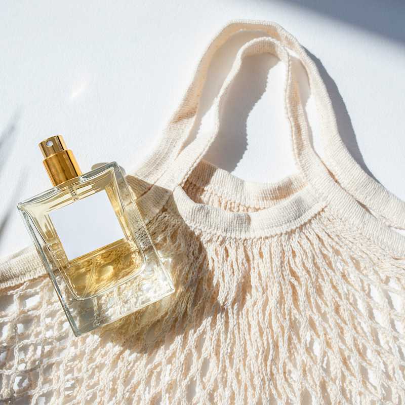 Flakon mit goldenem Sprüher und Häkeltasche