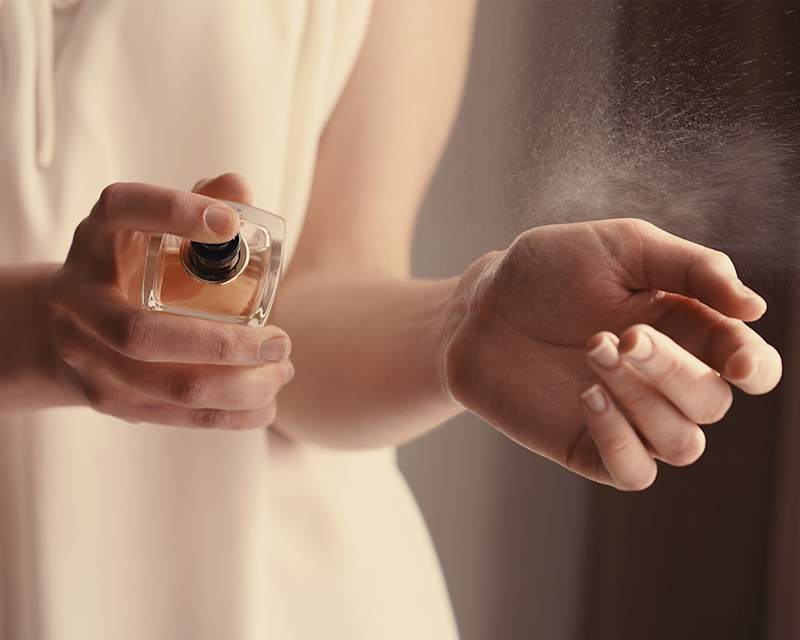 Frau sprüht Duft auf ihr Handgelenk