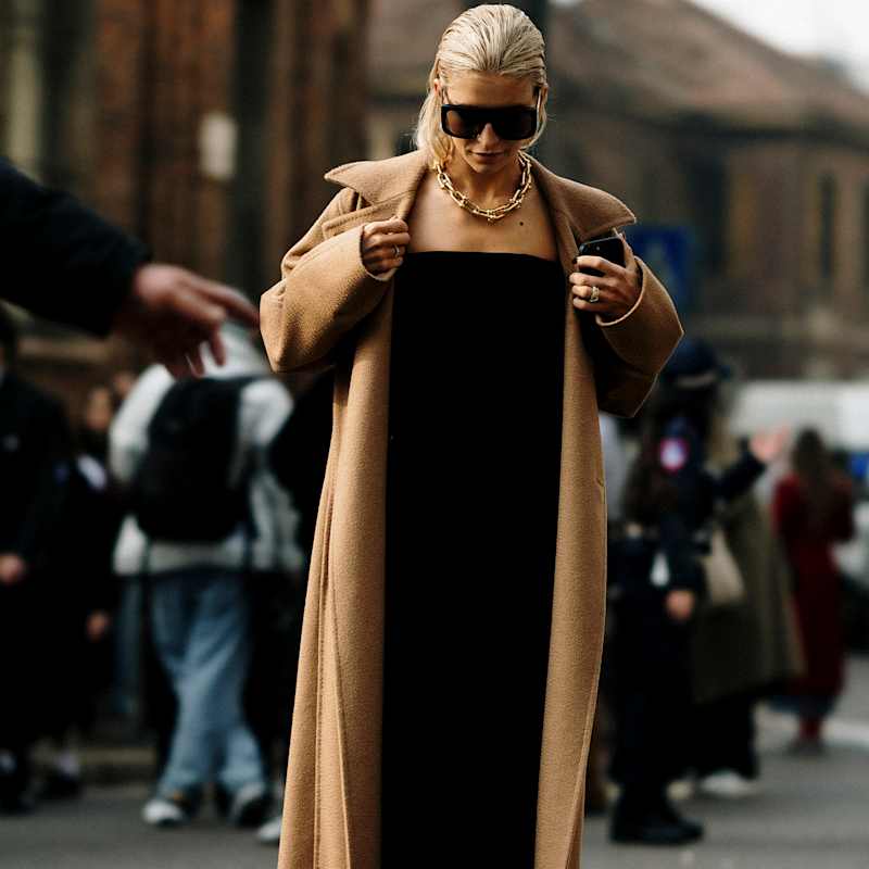 Frau trägt einen beigen Mantel zu einem schwarzen All-over-Look