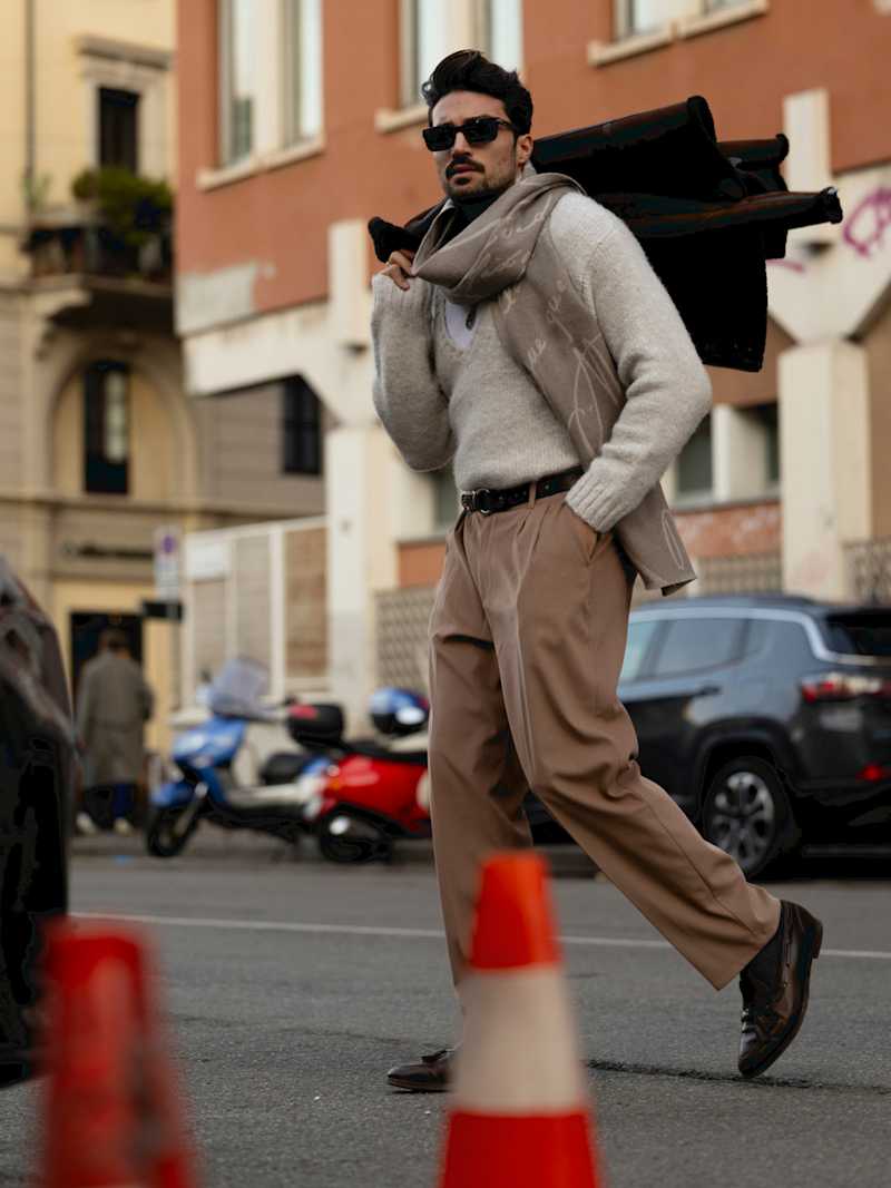 Mann trägt Wollpullover, Stoffhose und Schal im beigen, monochromen Look