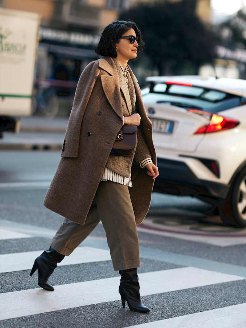 Frau trägt beigen, monochromen Look mit Wollmantel, Stoffhose und Stiefeletten