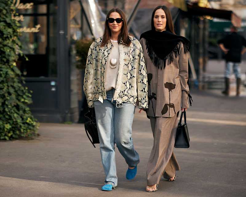 Zwei Frauen stehen nebeneinander: Eine trägt eine Jacke mit Animal Print, die andere einen braunen Hosenanzug 