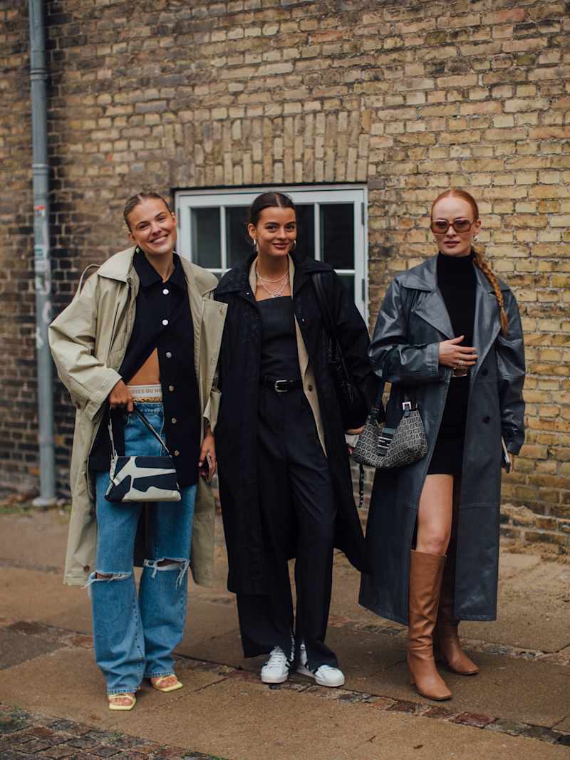 Drei Frauen stehen nebeneinander und tragen jeweils lange Mäntel über Strickjacken und Blazer als Lagen-Look