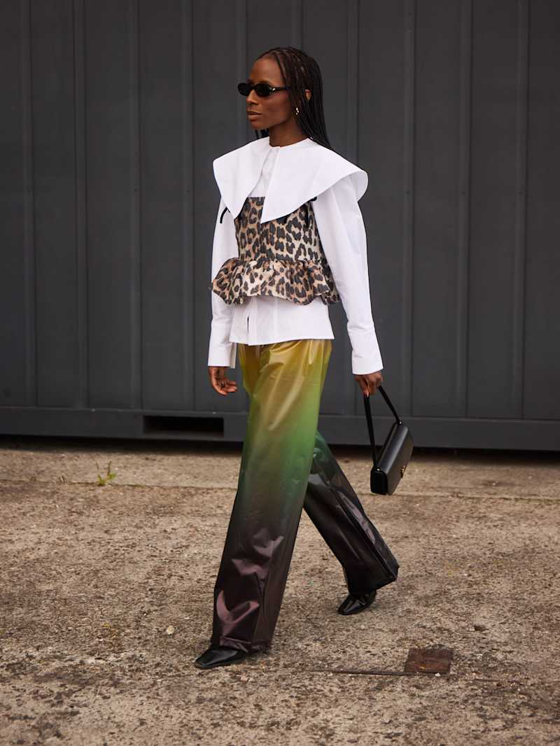 Frau trägt eine Hose mit Ombre-Verlauf und eine weiße Bluse, darüber ein Leo-Top  