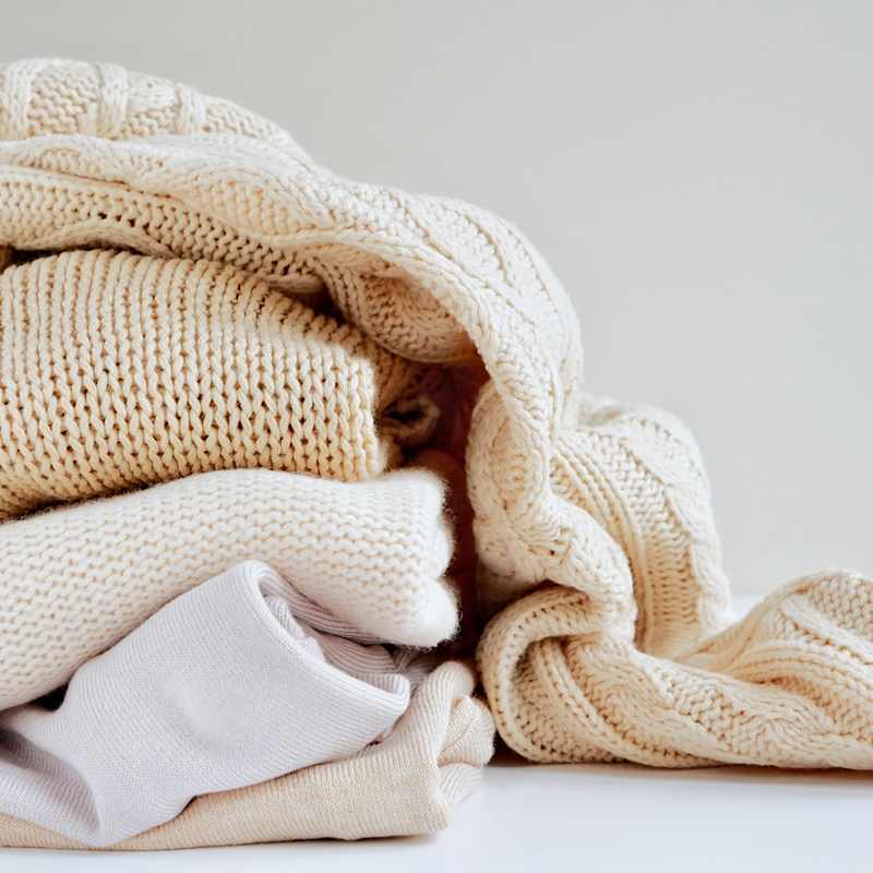 Kleiderstapel mit nudefarbenen Wollpullovern