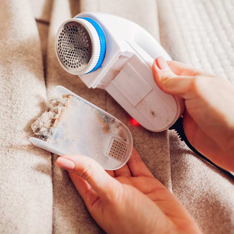 Geöffneter Fusselrasierer mit beigen Fusseln gegen Pilling