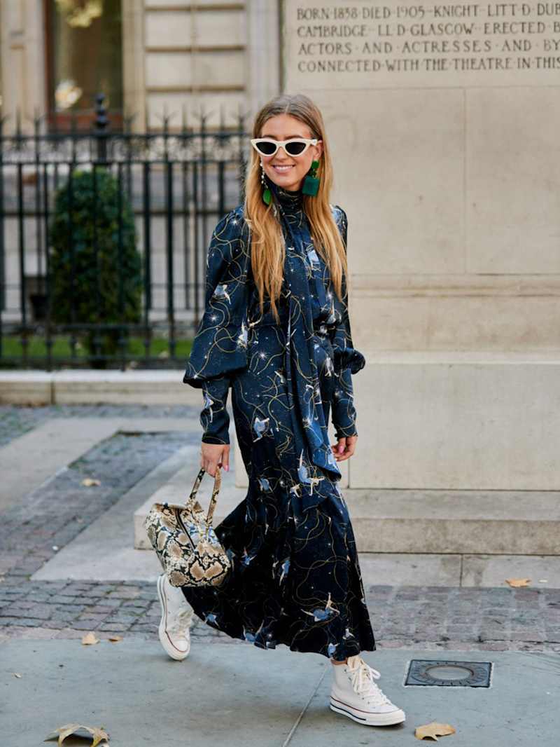 Frau trägt ein langes, dunkelblaues Kleid zu weißen Sneakern