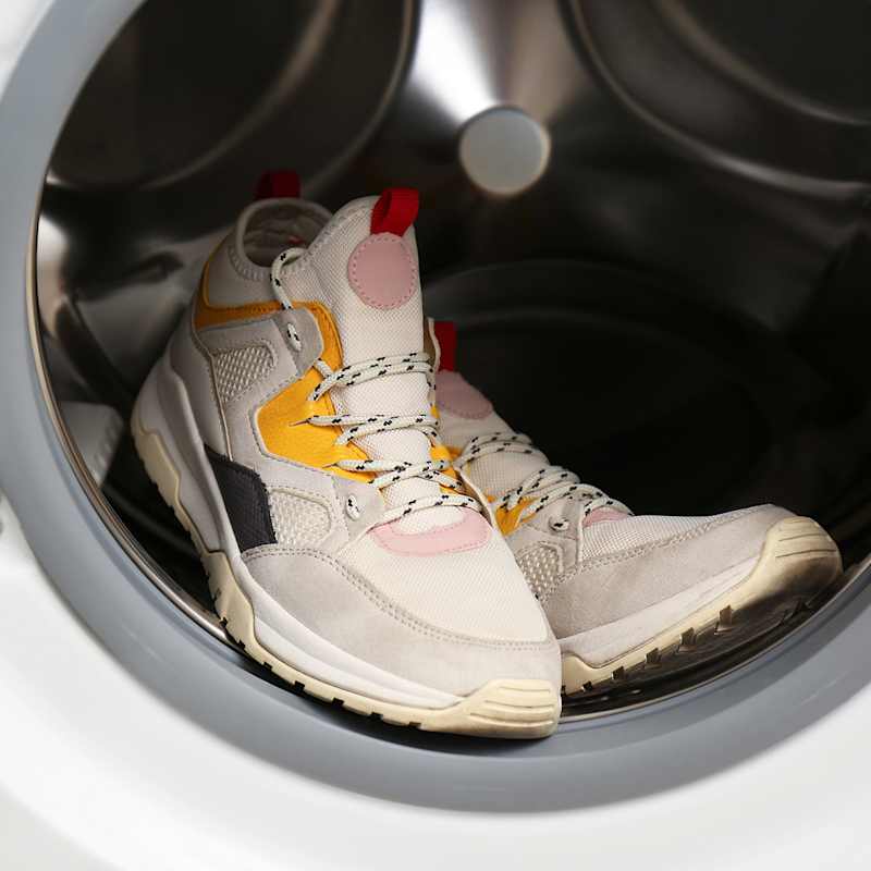 Bunte Sneaker liegen in der Wäschetrommel der Waschmaschine