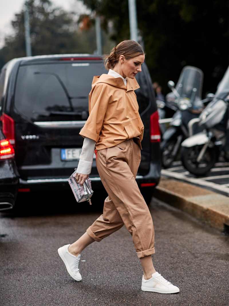 Frau trägt weiße Sneaker zum hellbraunen Leder-Outfit