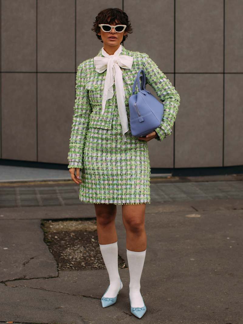 Frau trägt Kostüm mit Kurzjacke und Minirock aus Bouclé in cremeweiß-grün kariert
