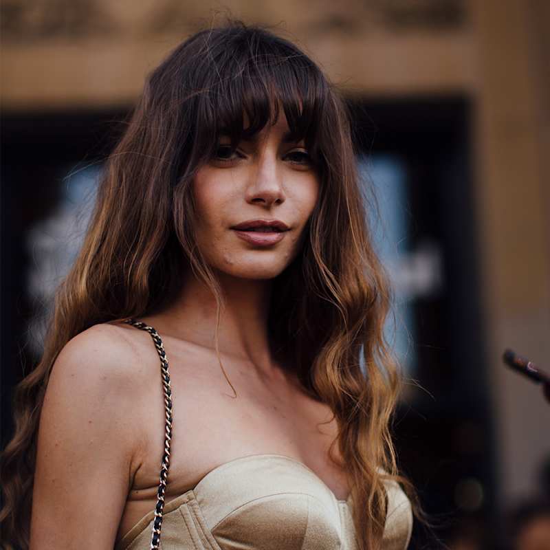 Brünette Frau mit welligen Haaren trägt Long-Pony