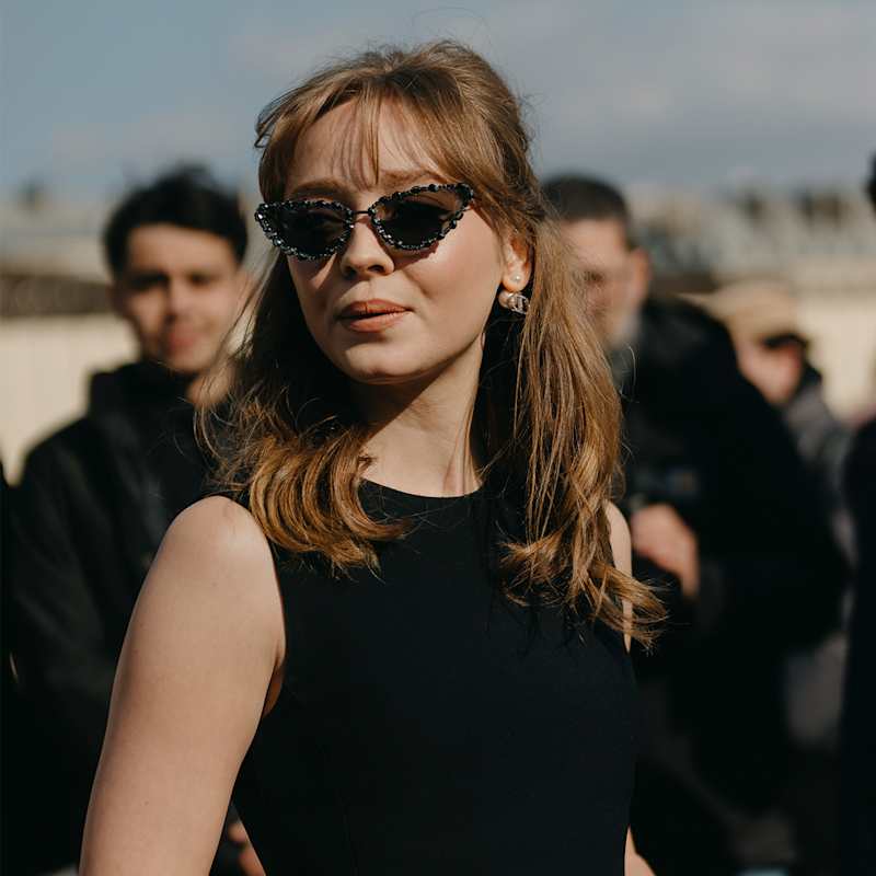 Dunkelblonde Frau mit mittellangen Haaren trägt Birkin Bangs