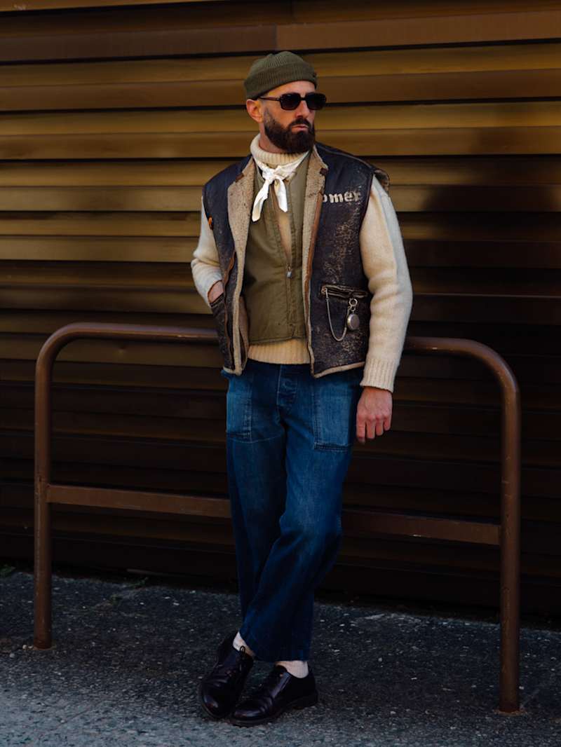Mann trägt Lederweste über einem Strickpullover zur Jeans